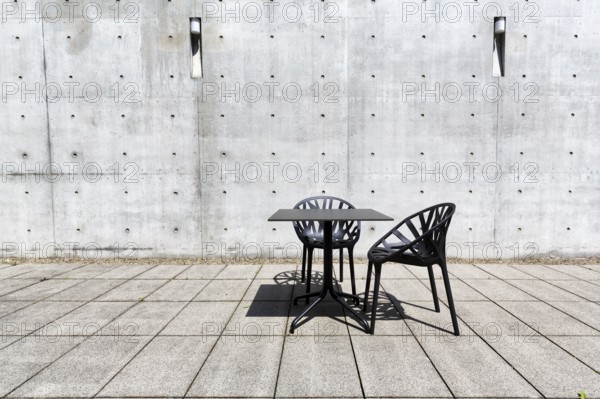 Black table and two plastic chairs in the courtyard made of exposed concrete, architect Tadao Ando,