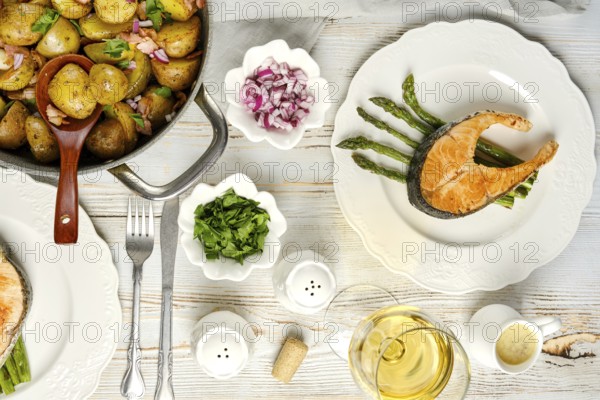 A beautifully arranged meal featuring a salmon fillet on asparagus, accompanied by seasoned