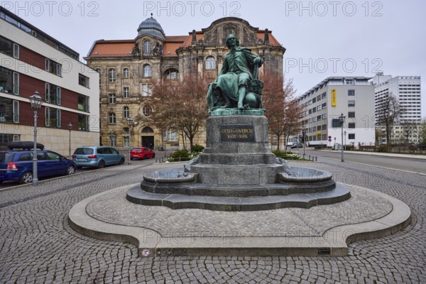Monument to Otto von Guericke, pavement made of cobblestones, lantern, parking lane with vehicles,
