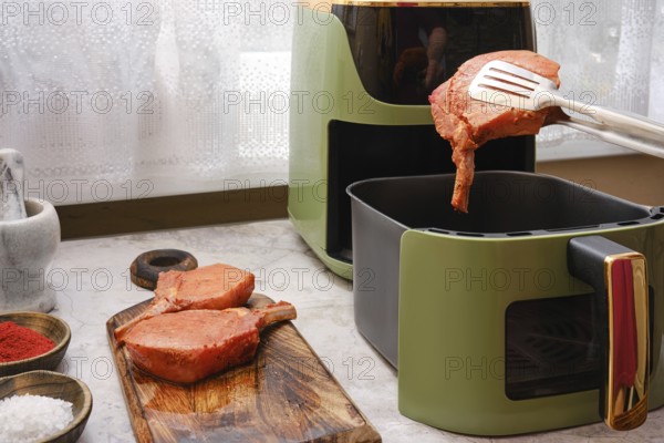Thick pork rib chops are being cooked in an air fryer, showcasing the ease of preparing tender meat