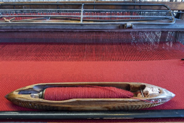 Old loom in the clothmaking museum in Bramsche, Lower Saxony, Germany, wooden shuttle on red fabric