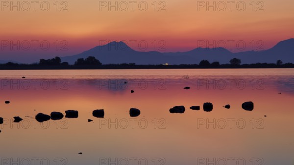 Dusk at the lake with dramatic sky and mountain silhouettes, salt lake, Tigaki, nature reserve,