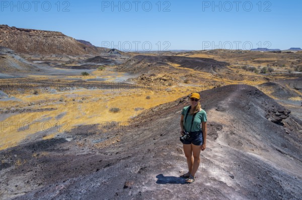 Tourist, Dry landscape with yellow grass and black volcanic hills, Burnt Mountain, Damaraland,