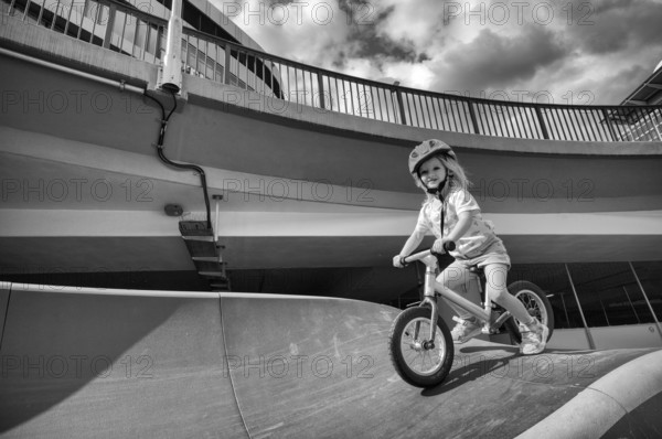 Girl, blonde, 3 years, laughing, riding with bicycle, bike, crash helmet, subway, urban, concrete,