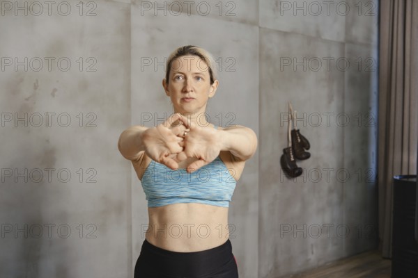 A fitness enthusiast is engaged in warm-up stretching exercises in a training space. The individual