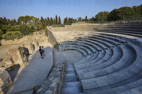 Ancient amphitheatre with stone steps and a few visitors, surrounded by nature, Ancient Theatre,