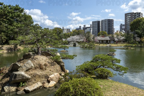 Shukkei-en with Sekisui-gan stone formation, green plants, trees and Koko-kyo stone bridge over