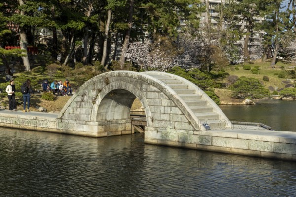 Shukkei-en with Koko-kyo stone bridge over Takuei-chi pond in spring, historical Japanese strolling