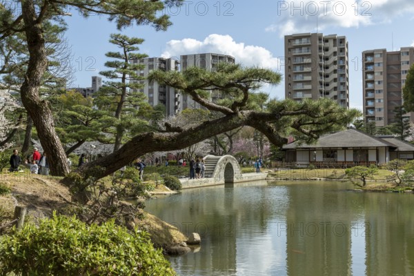 Shukkei-en with Seifukan teahouse and Koko-kyo stone bridge over Takuei-chi pond in spring,