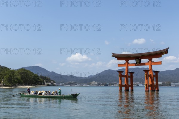 An excursion boat with tourists passes through the torii in the water, sight, tourist attraction,