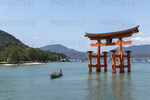 An excursion boat with tourists passes through the torii in the water, sight, tourist attraction,