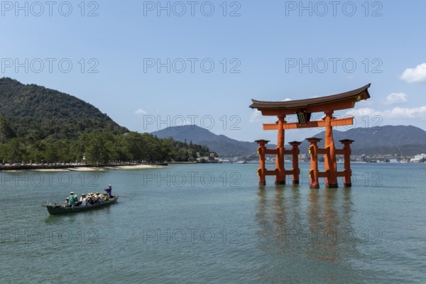 An excursion boat with tourists passes through the torii in the water, sight, tourist attraction,