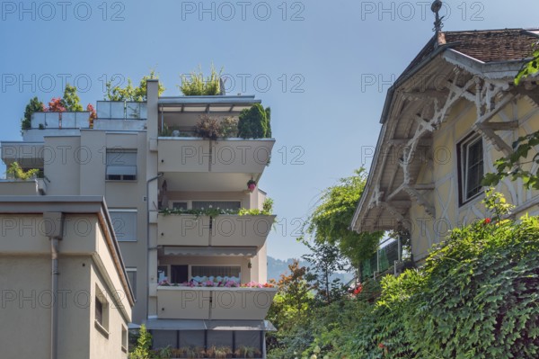 Grey façade, green flat roof and concrete balconies with floral decorations and old villa,