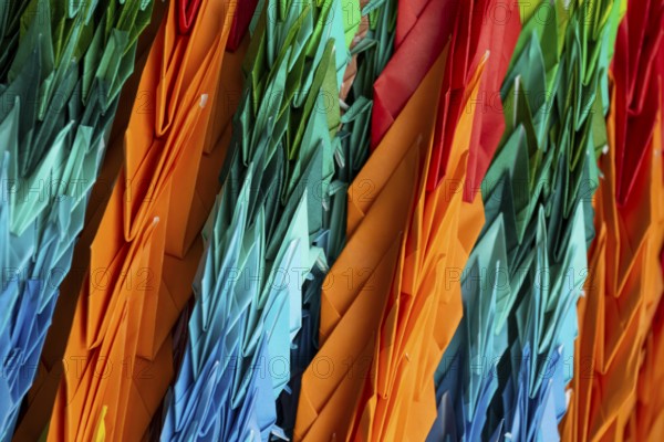 Chains of colourful origami cranes made of paper as a sign of peace in the Peace Park, close-up,