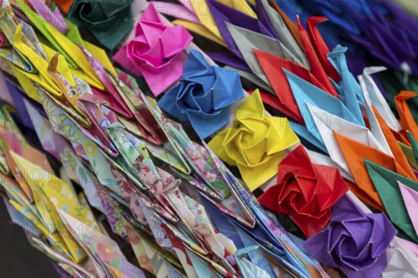 Chains of colourful origami cranes made of paper as a sign of peace in the Peace Park, close-up,