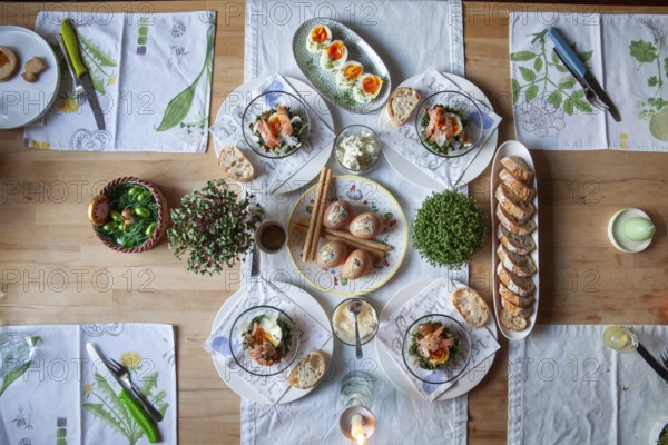 A stylishly laid table with a selection of fresh dishes, decorated with herbs and candlelight,
