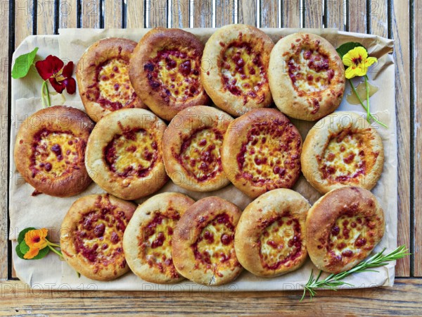 Small pizzas on baking board decorated with flowers and rosemary, bird's eye view, Lower Austria