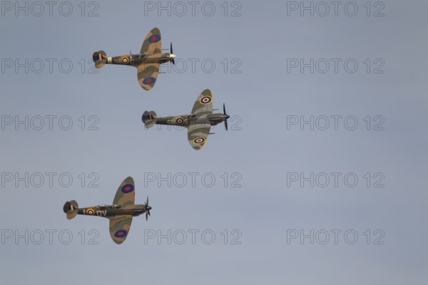 Supermarine Spitfire three warbird military aircraft in Royal air force RAF colours flying,
