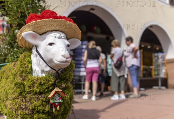 Kitsch in Black Forest style. A sheep with a Bollenhut and cuckoo clock. Freudenstadt,