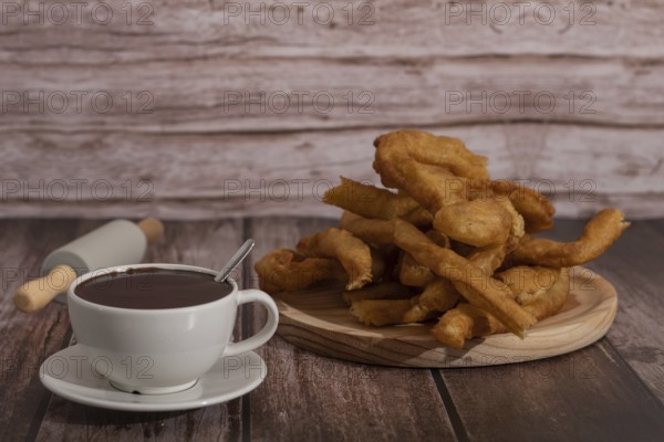 Cup of hot chocolate with freshly made churros on wooden background typical spanish breakfast on