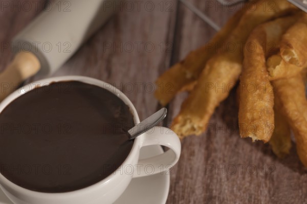 Cup of hot chocolate with freshly made churros on wooden background typical spanish breakfast on