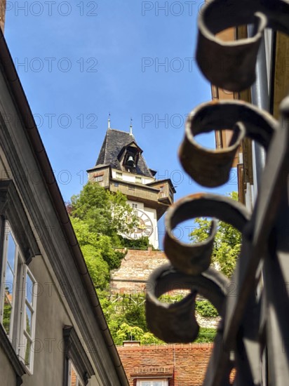 Architecturally richly decorated tower behind a forged fence with a clear sky Graz Clock Tower Graz