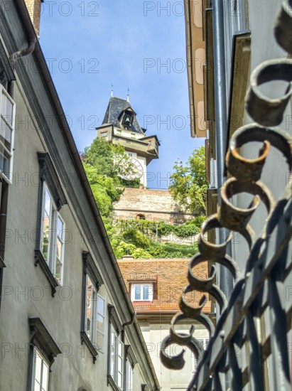 View through narrow old town street to a historic tower, flanked by old buildings Graz Clock Tower