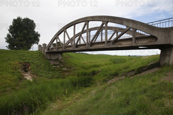 A concrete bridge over a grassy landscape that radiates peace and serenity Perschling flood channel