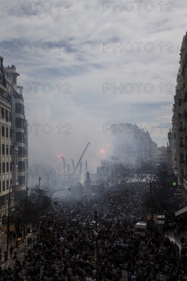 Tightly packed crowd under clouds of smoke on a city street MascletÃ¡ de Fallas