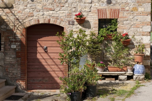 Tuscany country house detail with flower bench planter next to old wooden door quarry stone wall,