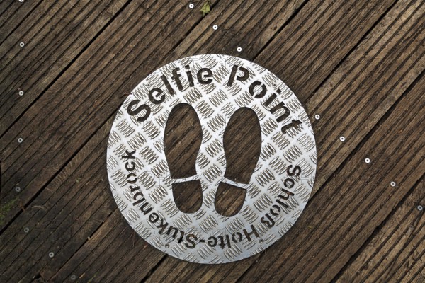 Selfie point, metal plate, shoe prints on a plank path at the source of the River Ems near Schloss
