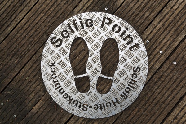 Selfie point, metal plate, shoe prints on a plank path at the source of the River Ems near Schloss