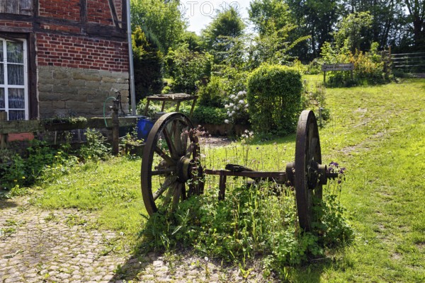 Rusted metal wheels on an axle, decoration in a garden, country inn in summer, Rischenau, LÃ¼gde,