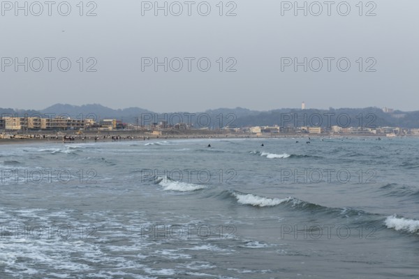 Houses on the seafront and surfers in the surf at dusk on the beach in Kamakura, Kanagawa