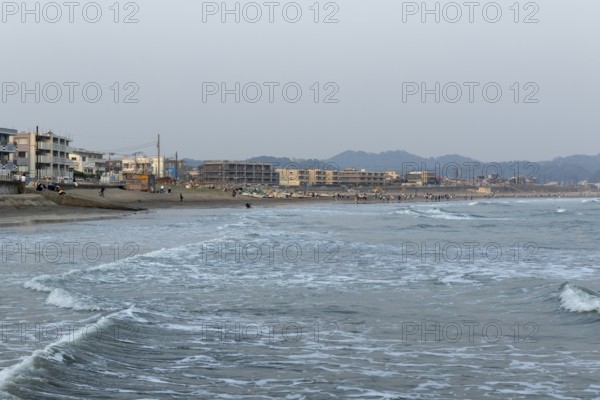 Houses on the seafront and surfers in the surf at dusk on the beach in Kamakura, Kanagawa