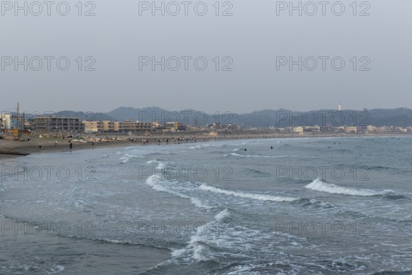 Houses on the seafront and surfers in the surf at dusk on the beach in Kamakura, Kanagawa