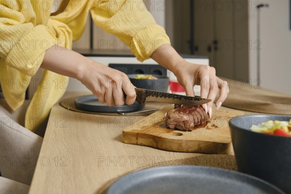 A person skillfully slices a perfectly cooked duck breast on a wooden cutting board in a stylish