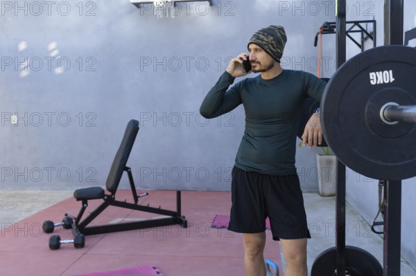 Athlete taking a break from an intense workout, leaning against a weightlifting rack while engaged