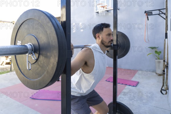 Focused male athlete lifting weights and performing squats in a home gym, showcasing strength and