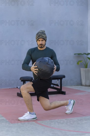 Athlete performing lunges while gripping a medicine ball, showcasing strength and balance during an