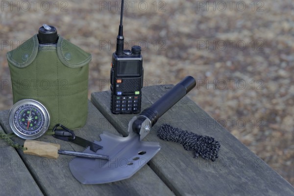 Essential survival gear including walkie talkie, compass, folding shovel, and fire starter are