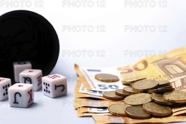 White dice with black letters and red dots are falling from a black dice cup, lying near some 50