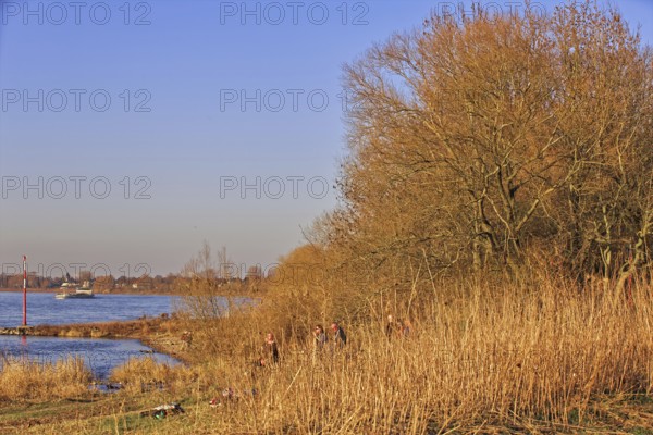 Tranquil river landscape with people sitting on the bank enjoying the late afternoon sun,