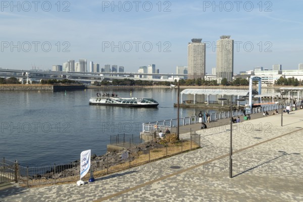 Strollers on the promenade and futuristic Tokyo Cruise Water Bus Queen Emeraldas, excursion boat