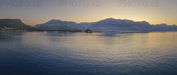 Panoramic dusk scene in Kemer, Turkey, showing the town illuminated coastline and beach, reflected