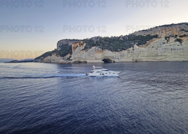 Vibrant evening seascape with a boat cruising away on the blue sea, near the Pirate Cave in Kemer