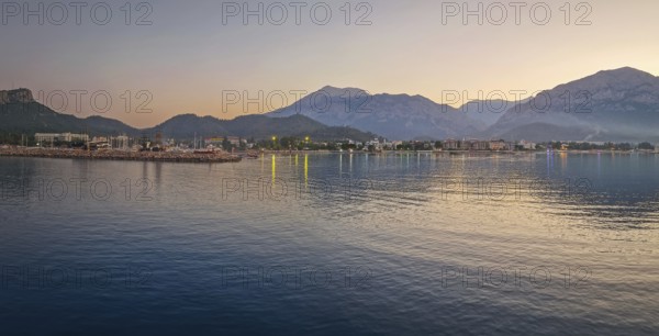 Dusk scene in Kemer, Turkey, showing the town illuminated coastline and beach, reflected