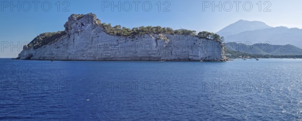 Vibrant seascape panorama with beautiful Turkish mediterranean coastline lined with tree covered
