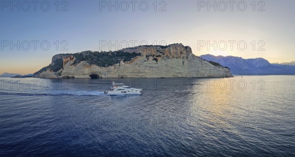 Evening seascape panorama with a boat cruising away on the blue sea, near the Pirate Cave in Kemer