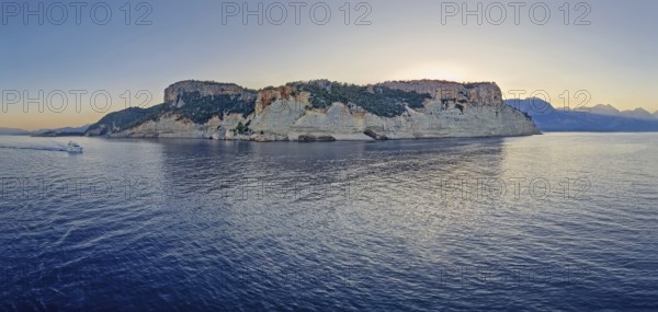Evening seascape panorama with a boat cruising away on the blue sea, near the Pirate Cave in Kemer
